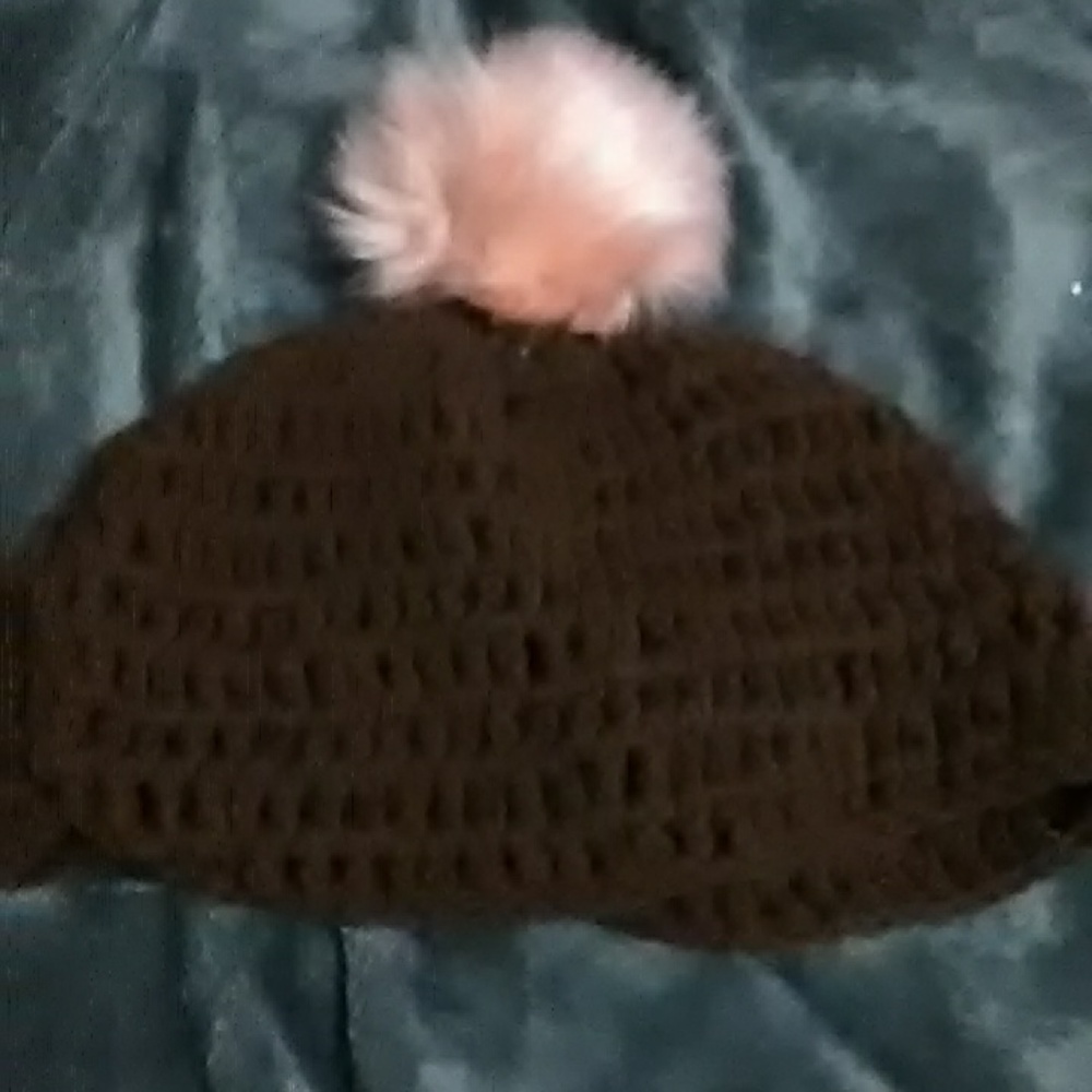 A kids hat with a pom pom on it